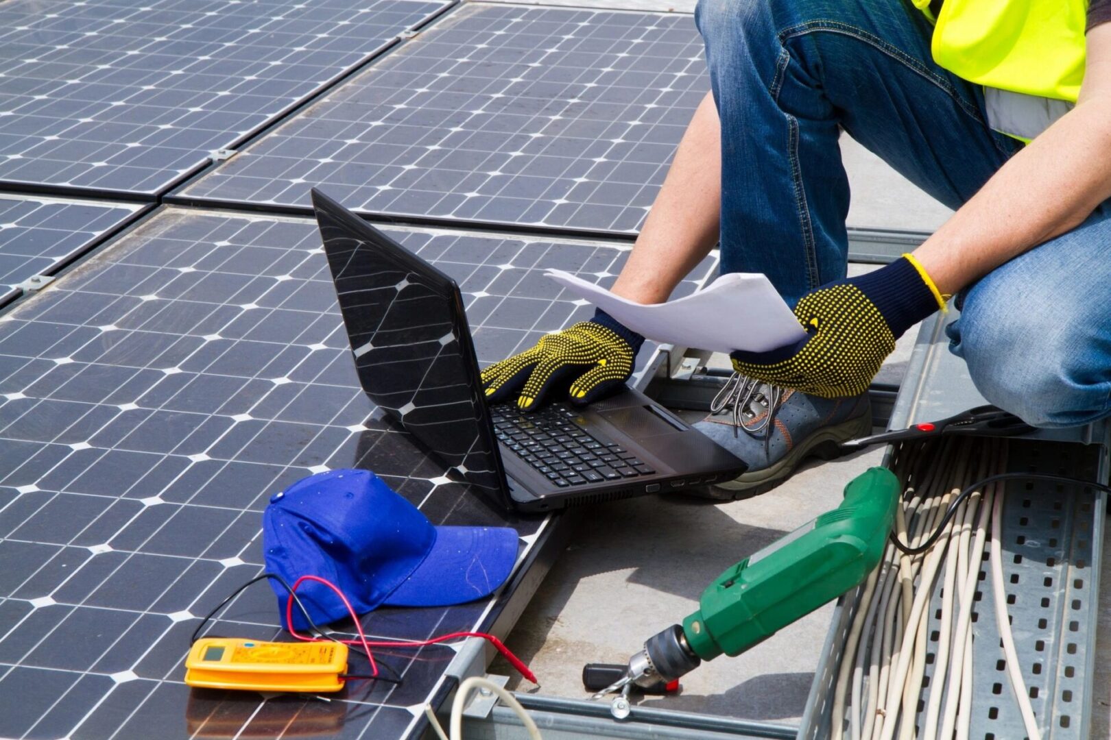 Solar panel technician using laptop and tools