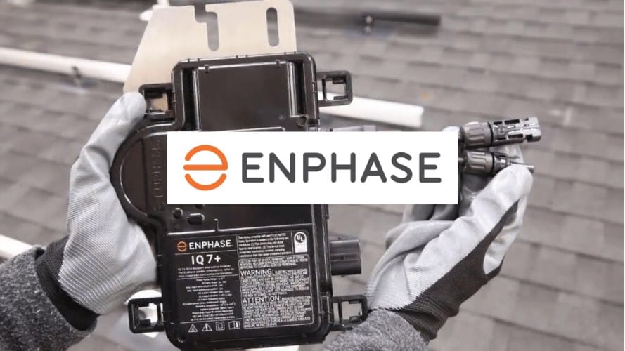 Gloved hands holding Enphase IQ7+ microinverter